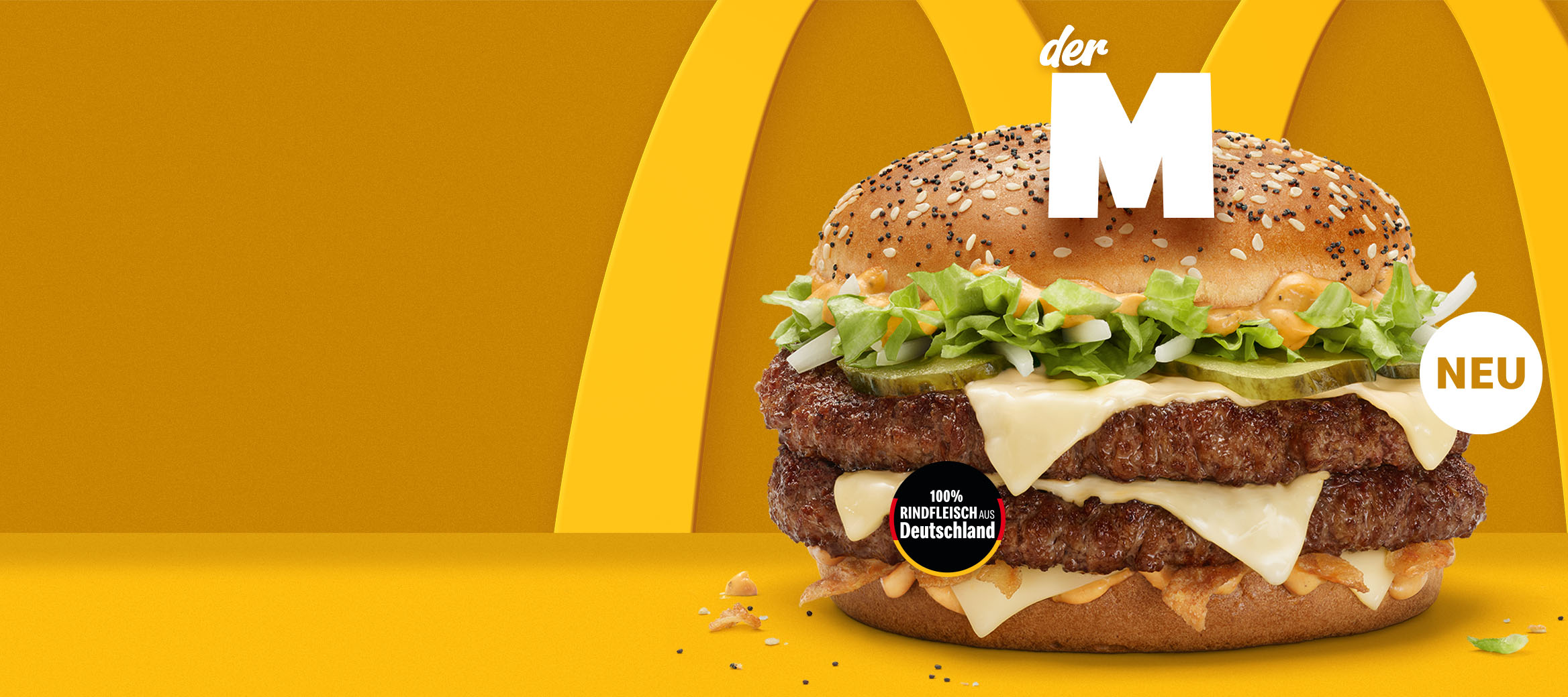 Wir sehen den Burger Der M mit der Überschrift: Zwei Hände voll Geschmack