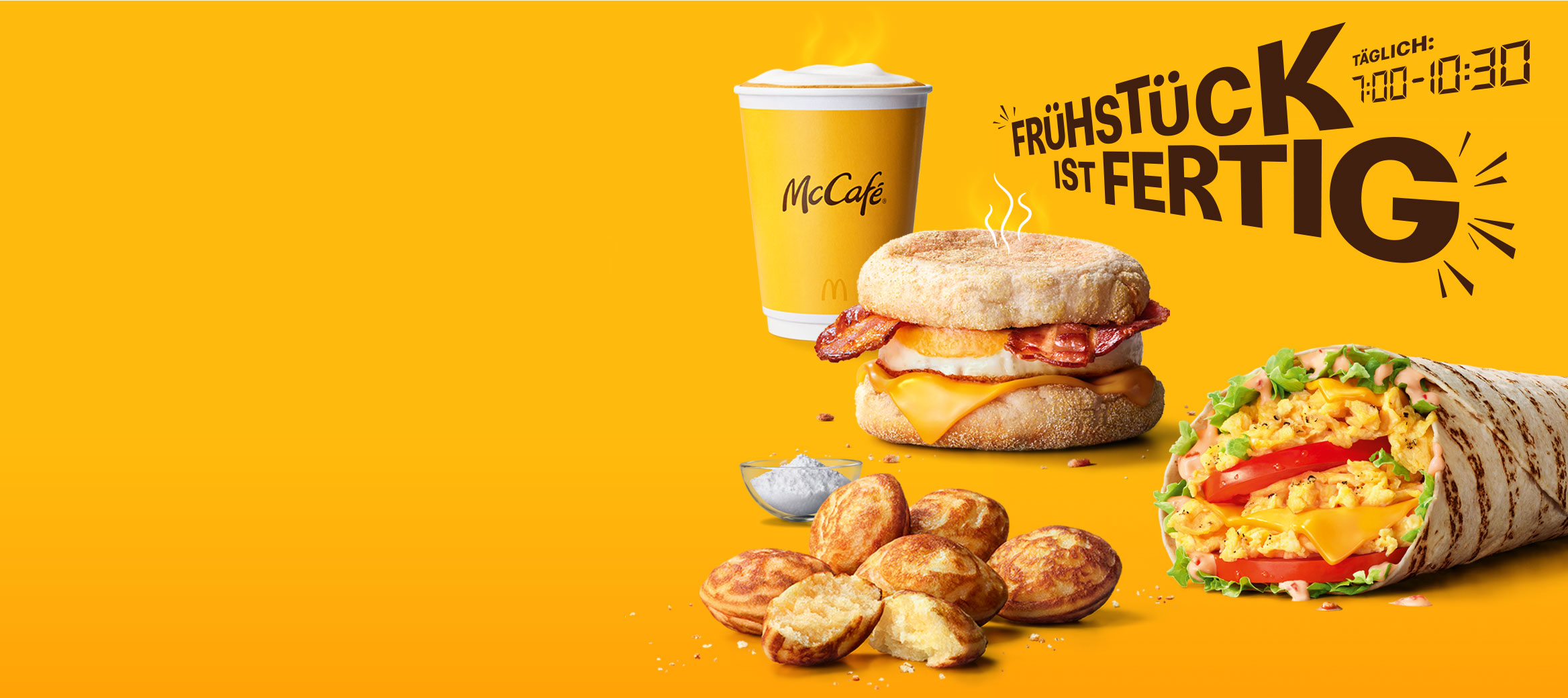Das Bild zeigt die Überschrift „Frühstück ist fertig! Täglich von 7:00 bis 10:30 Uhr". Daneben sehen wir einen Becher Kaffee, einen McMuffin Bacon & Egg, Mini Pancakes und einen McWrap Rührei Cheese.