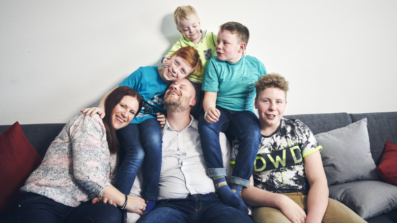 Familie mit vier Söhnen posiert vergnügt auf dem Sofa