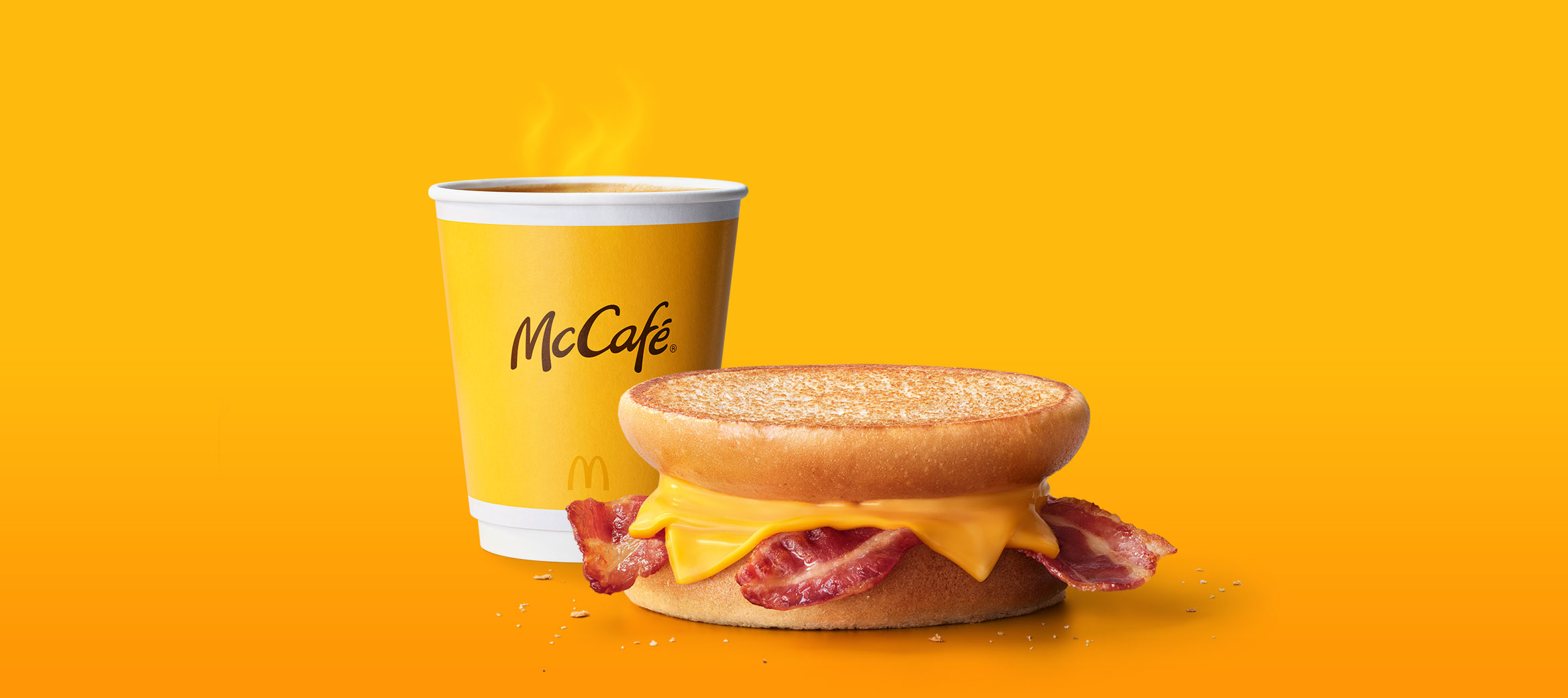 Das Bild zeigt einen kleinen Becher Kaffee und ein McToast® Bacon & Cheese.