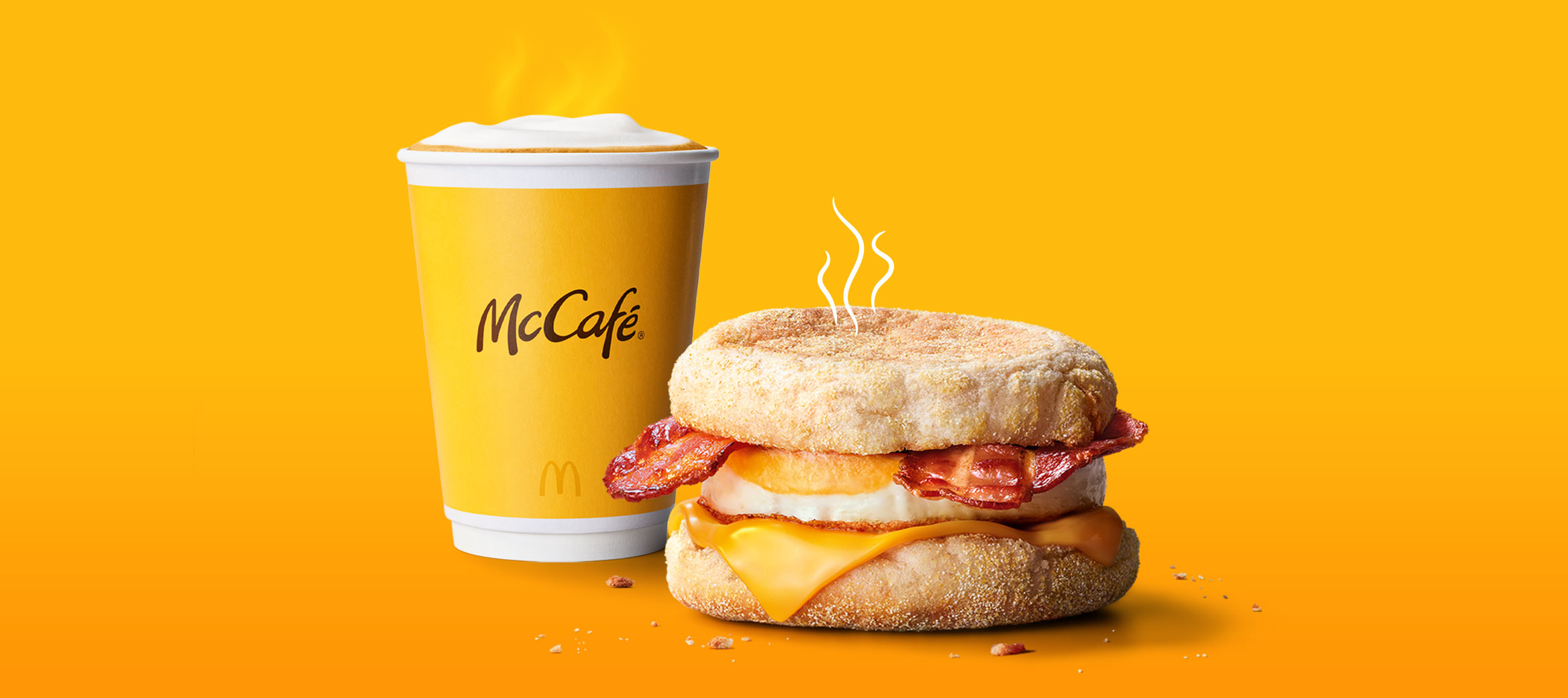Das Bild zeigt einen dampfenden Becher Kaffee und einen McMuffin® Bacon & Egg.