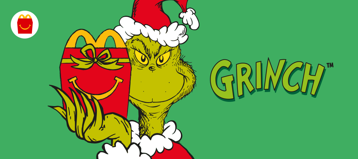 The Grinch wearing a Christmas hat holding a red Happy Meal box with a smile and a green bow