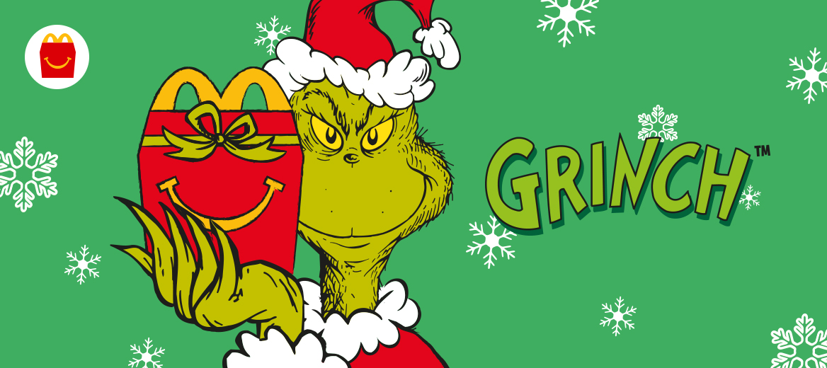 The Grinch wearing a Christmas hat holding a red Happy Meal box with a smile and a green bow