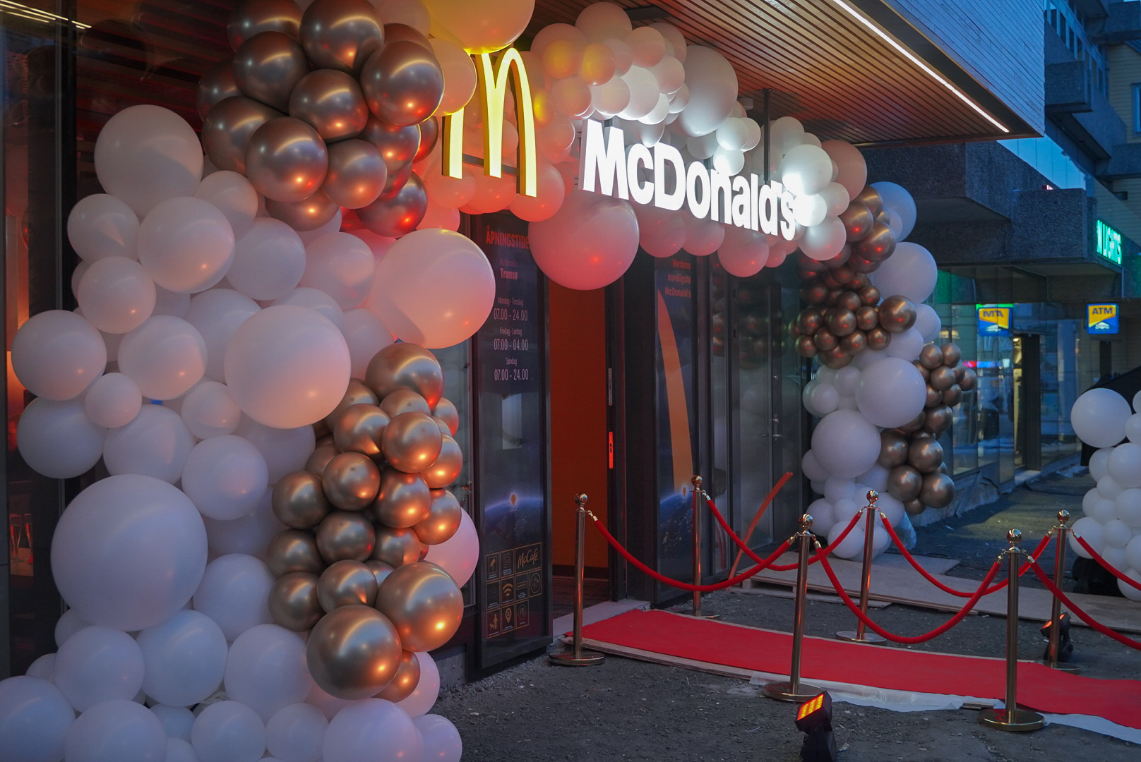 Festlig dekorasjon med ballonger og rødløper utenfor McDonald's restaurant. Foto