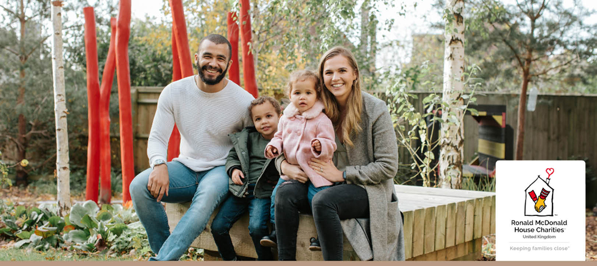 Family sitting on a bench in front of a mural.